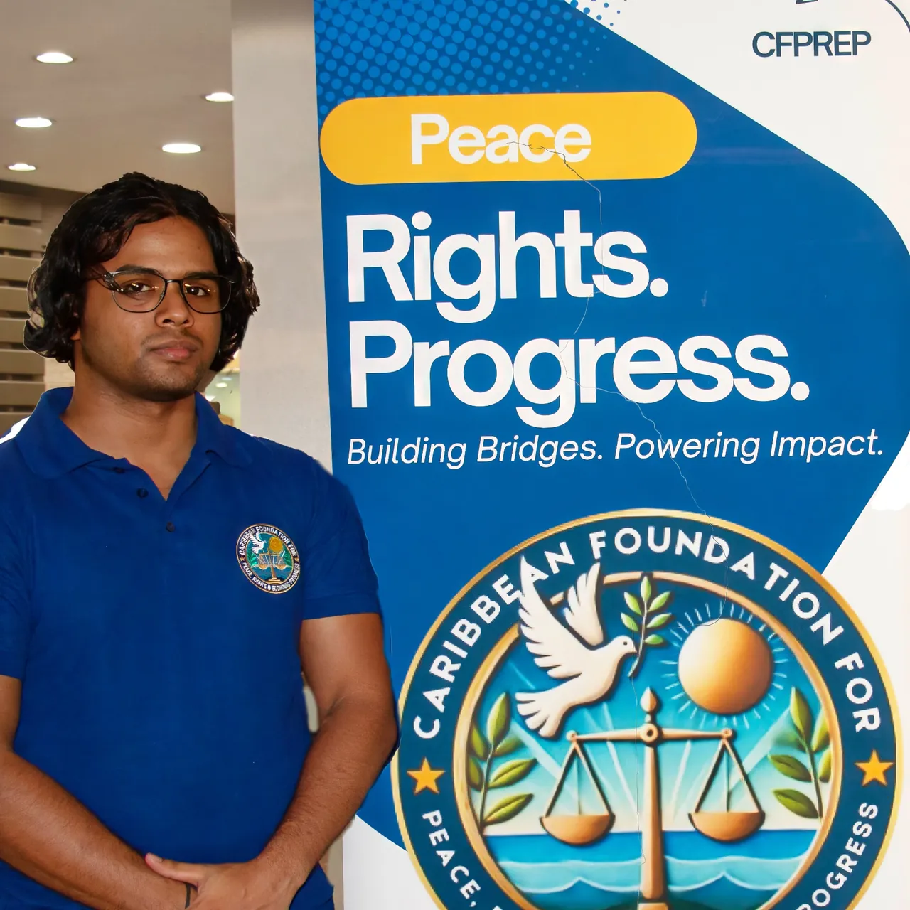 Samir standing beside a CFPREP banner that reads Peace, Rights, Progress